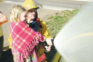 Colvill volunteer firefighter Bob Morrisson helps Elsa Gerry spray water at a recent demonstration of firefighting procedures and techniques that was given to Great Expectation School. All of the children got a chance to spray water, and all did a tremendous job!