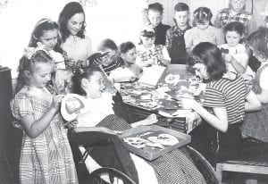 Janet Schuster Nagy shared this photo of the “Willing Hearts and Hands Club” that met with their friend Patty Mulligan (in wheelchair) to make cards to send to other kids with polio. There are a few children that Janet doesn’t know or is uncertain of their identity—do you know who they are? (L-R) Joan Toftey, Rhea Berglund, Donna Smith, Janet Lindquist, Margaret Johnson, Marian Berglund, Unknown, Russell Smith, Rosemary Smith, Janet Schuster, Dick Berglund (behind), Helen Jackson, Bobby Creech.