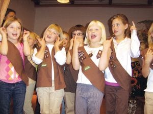 Cook County Girl Scouts held their annual investiture and rededication ceremony on Thursday, Oct. 14 at St. John's Catholic Church. Above: Standing in front, Brownie Troop 4077 members (L-R) Saira Smith, Abby Stoddard, Izabella Sparks and Hazel Kemp sing with their troop at the Girl Scout ceremonies held last week. The ceremony included rededication of all Girl Scout a meeting of new a weaving together making new friends time a closing flagceremony. Sarah Toftey completes investiture and bridging. is a member of Cadette 4113.