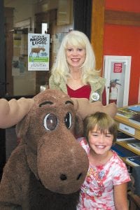 Last Friday there were reports of a moose loose in Grand Marais. And sure enough, after some diligent sleuthing…. some ears to the ground and fingers in the wind, the moose was found in the Grand Marais Public Library. Here the moose takes time off from “browsing” books to allow himself to be shot (not fatally) with Jessica MacCudden and, standing behind to keep the moose in line, Patsy Ingebrigtsen. No word yet whether or not the DNR tried to capture the critter, which, coincidentally enough, shows up every year just in time for Grand Marais Area Tourism’s Moose Madness.