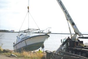 Tim Mackey’s boat gets a lift from Edwin E. Thoreson, Inc.'s crane. The boat was beached last week in the big windstorm. Bertil Lindquist’s sailboat was also run aground in the same storm and was also heavily damaged.