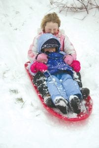 Hang on! Annie Lynch, 7, and Emma Crook, 3, of Grand Marais were some of the many kids who enjoyed the heavy wet snow that fell on Saturday. They were ready for sledding on Sunday.