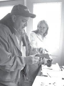 Archaeologist Sue Mulholland with Todd Lindahl at the Cook County Historical Society Museum, looking at a fur trade-era ax believed to be British. It is one of the artifacts in the Cook County Historical Society collection, which also includes a fully grooved stone believed to be a carpentry tool as old as 3,000 years and a copper tool found in Grand Marais in the 1920s, believed to be as old as 6,000 years.