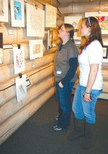 Cook County Schools students are displaying a wide variety of artwork at Johnson Heritage Post through January 2, 2011. Students, teachers, and community members enjoyed the opening of the show Friday, November 19, 2010. Annika Stone and Lauren Murray take in some of the artwork created in Art Teacher Mary MacDonald’s classroom.