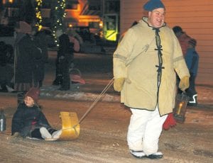 Karl Koster pulls his daughter Alice on a toboggan through the streets of Grand Marais during the annual Christmas Parade. Though the temperatures hovered around 18 above zero, Karl and his daughter seemed as warm as the smiles on their faces. Karl and Alice were representing the Grand Portage National Monument.