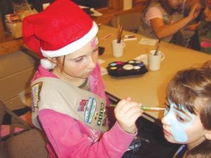 Santa’s helpers! The Girl Scout Northern Lights Service Unit held a Santa’s Workshop at the Cook County Community Center to help kids find the perfect gift for mom or dad. They also had a bake sale, crafts for kids and face painting. Top: Natassja Sheils concentrates while she works on Laura Ashford-Ball. Natassja was one of many face-painters. Above: Daphne Lacina and Lucy Shaw wrap a special Christmas gift.