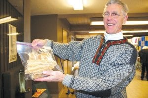 The Julefest at Bethlehem Lutheran Church on Saturday, December 11 was a delightful Christmas event, with the crowning of St. Lucia, sugary Scandinavian treats, and lovely music. Top: What would a Scandinavian Christmas event be without lutefisk? Commissioner Jim Johnson shows off some of the delicacy for sale, courtesy of the late Fred Anderson of Grand Marais, who last year ordered more than his family could eat. Above: Mary McElevey lights the traditional Julefest candles at the tables filled with Scandinavian specialties.