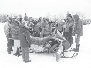 Twenty-seven youths participated in the 2010 Department of Natural Resources Snowmobile Safety Training. On Saturday, December 11, students and volunteer instructors gathered at the old airfield by Devil Track Landing to practice what they learned in the classroom. Above: Instructor Brad Thompson demonstrated how to change a drive belt and then Instructor Eric Nelms gave some other snowmobile pointers. Left: MN DNR Conservation Officer Mary Manning explains the snowmobile safety obstacle course as a student prepares to take off.