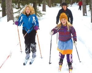 Lucy Callender skijoring with Lucy the dog while Robin Henrikson speeds alongside on her own power. Peter Henrikson follows the excited girls.