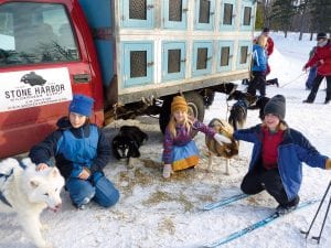 The kids in the Cook County Y-Ski program got a special treat on Tuesday, February 15—a skijoring outing at George Washington Pines in Grand Marais. The adventure was sponsored by Frank and Sherri Moe of Moetown Kennels and Stone Harbor Wilderness Supply. Pictured here getting to know the dogs are (L-R) Klaus Bottorff, Robin Henrikson, and Finn Garry.