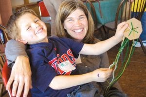 Right: Sara Mairs and son Will Steinhacker from St. Paul try out Kumihimo Braiding during Saturday’s Fibers for Kids program. Taught by Northwoods Fiber Guild member Maxine Linehan, Kumihimo is a form of decorative braiding that originated in Japan. Participants use simple disks to interlace colorful strands of fibers into cylindrical braids.