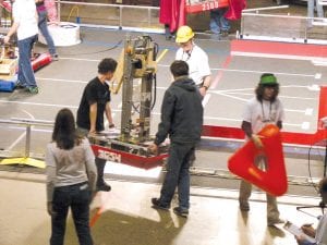 Left: Team members carry the Ice Storm robot onto the field of competition at the DECC.