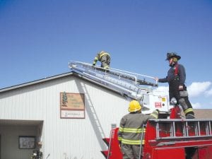 Members of the Grand Marais Fire Department underwent training on how to use the department’s new ladder truck on Saturday, April 2. Erik Jankila (standing on truck) of Mesabi Range Community & Technical College and the Hibbing Fire Department conducted the training on use of a telesquirt firefighting vehicle. Practicing use of the ladder on the Cook County Community Center roof is firefighter Gideon Silence. Randy Bockovich waits for his turn to climb.