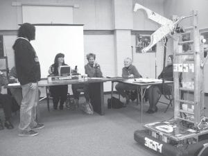 School board member Jeanne Anderson drives the Cook County High School robotics team robot at the April 19, 2011 school board meeting. The team brought the robot to the meeting to demonstrate it for the school board. (L-R) Max Simonowicz (standing), Jeanne Anderson, Deb White, Mary Sanders, and Superintendent Beth Schwarz.