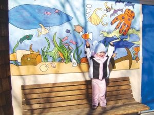 Sophia Sheenan, daughter of Nick and Isabella Sheenan of Grand Marais, posed in the warm sunshine on April 14, 2011 in front of the mural outside the Grand Marais Municipal Pool. Great Expectations Charter School students created and donated the mural last year. Pool programs for all ages are running full tilt, including a toddler time in the kiddie pool from 9:30 to 11:00 a.m on Tuesdays and Thursdays, concurrent with adult swim.