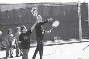 Under the fine tutelage of tennis instructor John Muus, a large group of elementary aged kids are once again being taught the basics of a game they can play into old age, if they so desire. Here John shows Jackson Fenner how to direct an overhand shot, and in the photo to the right, he instructs a little shaver on where to put his feet.