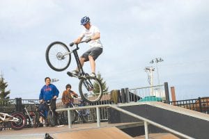 Left: Kids watched in amazement as the daredevil Twin Ports Trial Riders performed gravity-defying stunts in the North Shore Skate Park. Top: Becky Sturm of the Cook County Ambulance makes the proper adjustments to a bike helmet. Above: Jerry Hiniker of Superior North Outdoor Center conducts a safety inspection.