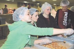 All age groups turned out to help with the Feed My Starving Children project that took place last Saturday in the Community Center in Grand Marais. Here, Sarissa Falk on the left and Ailee Larson, third to the right, join two teens from Two Harbors that came to help.