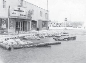 Although this photo was taken in 1960 because of an extreme weather event in downtown Grand Marais, it is one of the best historical photos of the old Shore Theater, which is being demolished this week. By the time the Cook County News-Herald goes to press, the theater should be a vacant lot. (See related information in Down Memory Lane on