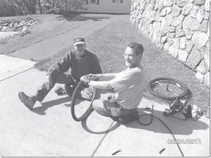 The WOW—Wheels for Workers program provides loaner bicycles for visiting international workers. The program is a project of the First Congregational Church Outreach Group. Rick Schubert and Jerry Lilja repair a tire for a WOW bike.