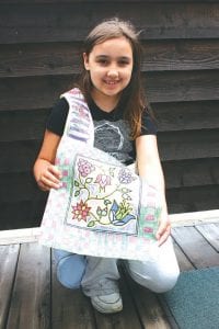 Third-grade essayist Madisen Foster shows the beautiful Ojibwe style shoulder bag she designed in Lorelei Livingston's class.