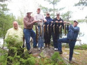 Fishing has been very, very, good on the Canadian side of Lake Saganaga. John Schei (left) guided the Baker family—Ken, Corrine, RuthAnn, Renee, and Marion. They happily show off their catch of walleye, trout, bass and pike.