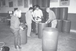 Dave Stark, a workshop presenter at the Small Footprint Living Fair at the Cook County Community Center in Grand Marais June 24 (second from left), demonstrates the construction of a rain barrel rainwater collection system.