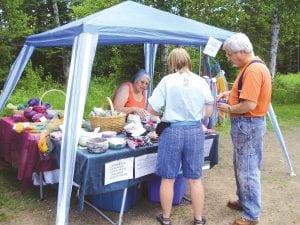 Michelle Hoy of Grand Portage assists Gayle and Dave Harvey of Grand Marais with their purchase at her booth filled with fabulous fiber arts pieces.