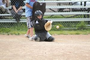 Above left: Eyes focused on the ball the same way a pro catcher would do, Cameron Roy looks the ball into his catcher’s mitt. Above: When she’s not pitching, Maranda Deschampe plays a mean third base. Left: Brad Wilson evokes memories of “Fire ballin' Bob Feller” as he gets ready to throw some heat.