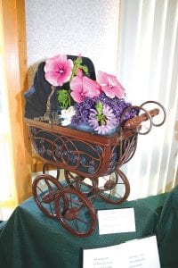 The theme of the 76th annual West End Garden Club show Saturday, July 16, 2011 at the Schroeder Town Hall was Posies ‘n Prose, and it showed off the impressive creativity of the West Enders. Arrangements used multiple flower species, containers, and props to illustrate books, poems, and literary themes. Clockwise from left: Baby Buggy Ride by Donna Utecht, The Florist’s Daughter by Trudy Hahn, Love Gardening! by Ginny Storlie, and Daisy Chain by Mary Jo Roche. Roche included an excerpt from Alice in Wonderland: “So she was considering in her own mind (as well as she could for the hot day made her feel very sleepy and stupid), whether the pleasure of making a daisy chain would be worth the trouble of getting up and picking the daisies, when suddenly a White Rabbit with pink eyes ran close to her.”