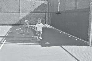 With hats in place and rackets firmly in hand, Grant Oberg (left) and Andrew Hallberg studiously perform a footwork drill at summer tennis practice. The boys participated in the QuicksStart: 8 & Under Division.