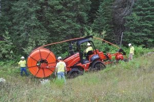 Work began last week in Lutsen to bring broadband Internet service to Cook County. Workers from MasTec North America will take about two years to complete the groundwork and lay the fiber optic cable. Here they unspool fiber optic cable and get it ready to bury in the trenches they have already dug.