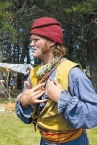 Voyageur Gene Tisdahl or “Henri,” explains the meaning of his tattoo. Voyageurs often were washed out of canoes and lost. If their bodies were found, tattoos would help identify them. Henri and others with the North West Company have a distinctive tattoo of a canoe passing Hat Point. The permanent India ink tattoos are created by Isaac Walters.