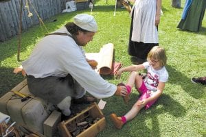 The shoemaker at Rendezvous Days checks the fit on the oxhide-soled shoes being tried by Madeleine Bartlow-Sibley, 6, of Eagan, MN.