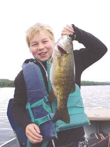 Left: Max McManus of Minneapolis shows off the 17-inch bass he caught while fishing with Joe Carlson of Joe’s Inland Fishing Guide Service. Guide Joe said this is not the biggest fish that Max has caught—last year he landed an 18.5-inch bass while fishing with Joe.