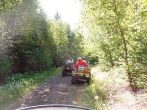 Above: ATVs take off on a lovely forest road in the Tom Lake area. The ride included a treasure hunt, with riders seeking things like cattails, flowers, and wildlife.