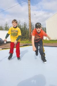 Tanner and Trevor Berglund try out the sample of synthetic ice purchased by Cook County. Their impression—synthetic ice is harder to skate on than real ice. But they had fun being in skates anyway.