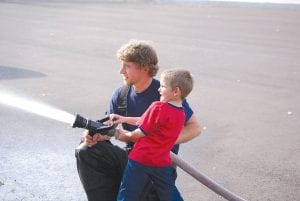 The Tofte Fire Department brought its ladder truck and the whole school got onboard! Tofte Firefighter Sam Crowley shows Conner Walsh how to work the firehose.