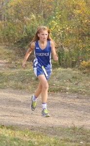 Above left: Jasmine Swenson ran a fine race in the Junior High division at the recently held Polar League conference meet held at Pincushion. Above right: Coach April Wahlstrom encourages her runners. Ben Seaton, with Joey Chmelik hot on his heels, made all-conference with a 9th place finish, while Joey just missed all-conference honors by placing 11th in the varsity 5K race. Right: Roman Schnobrich finished 6th in the JV race.