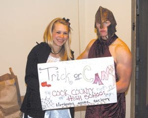 Left: Molly Zafft and Peter Warren, in their Halloween costumes, hold the sign promoting the event.