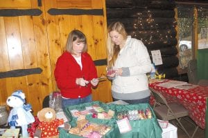 There were lots of smiles and laughter at the Grand Marais Community Craft Sale and Open House on Saturday, Nov. 26. Above: Shoppers checked out holiday items from local consultants like Judy Schmidt with “Scentsy.” Above right: Girl Scout Leader Arvis Thompson had a good time while selling pointsettias. Right: AnnaBelle Silence, 3, enjoyed a cookie—a “gingerbread guy!”