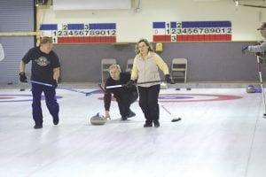 Above: Curling is a little bit like shuffleboard and chess played on the ice. Note the concentration of Brian Smith as he releases his rock. His wife, Joanne, and teammate Don Hammer are ready to sweep the ice when Brian tells them to. Hard sweeping keeps the rock straight, letting up, or not sweeping, allows the rock to curl, hence the name curling.