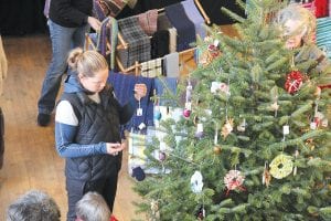 Above: The big tree in the center of the hall is loaded with handmade holiday ornaments from all the guild members. Hilja Iverson was one of the many shoppers selecting a special decoration. Right: Guild member Kay Rosenthal demonstrated fiber spinning. Jean Roberts checks out her handiwork.