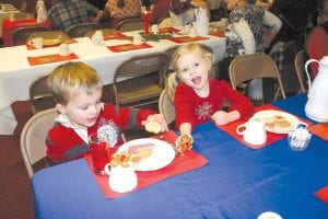 Enjoying the Julefest treats—especially the gingerbread men (pepparkaka)—were Reuben and Greta Youngdahl, who attended Julefest with their grandmother, Cathi Williams. Left: Mildred Thoreson provided music for Julefest. Philis Anderson joined her, playing her oboe for a few Christmas carols.