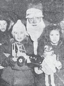 Pictured with Santa at the annual Leng’s theatre party for children held Dec. 17, 1955, are two of the prize winners, Patricia Freeberg and David Anderson, proudly holding their toys. Other prizes were won by 15 children. About 750 children from all parts of the county attended, according to a news item published in the Jan. 5, 1956 News-Herald.