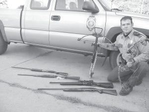 Conservation Officer Muyres shows some of the weapons that have been confiscated by the Minnesota Department of Natural Resources in the Ham Lake area. This year the DNR seized 134 firearms and bows in baiting related investigations.