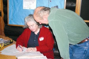 Cook County Republican Party officials Garry Gamble and Mary Petz review the precinct caucus sign-in. There was a record number of attendees at the caucuses held Tuesday, February 7 at the Cook County Community Center 4-H log building.