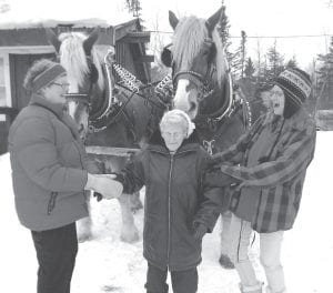 Geri Jensen (left) and Nikki Boostrom (right) help Gert Erickson to the sleigh at Okontoe. Notice that Bob the horse thinks Gert’s hat is delicious!