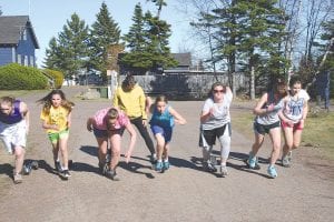 Track Head Coach April Wahlstrom (in back) stands on the blocks of two runners as the kids work on their starts. With almost 50 boys and girls out for track, Cook County High School will be well-represented at track meets this spring. Runners (L-R) Shae Morawitz, Hanna Borson, Lily Gruber-Schulz, Alyssa Martinson, Michaela Peterson, Melanie Stoddard, and Natassja Sheils.