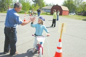 The Cook County Bike Safety Rodeo at the Cook County Community Center on Thursday, May 17 helped local kids get ready for safe bike riding this summer. The weather cooperated and it was a warm sunny day. Volunteers helped dozens of kids practice riding skills. Volunteer Rory Smith high-fives a young rider after she completes the practice course.